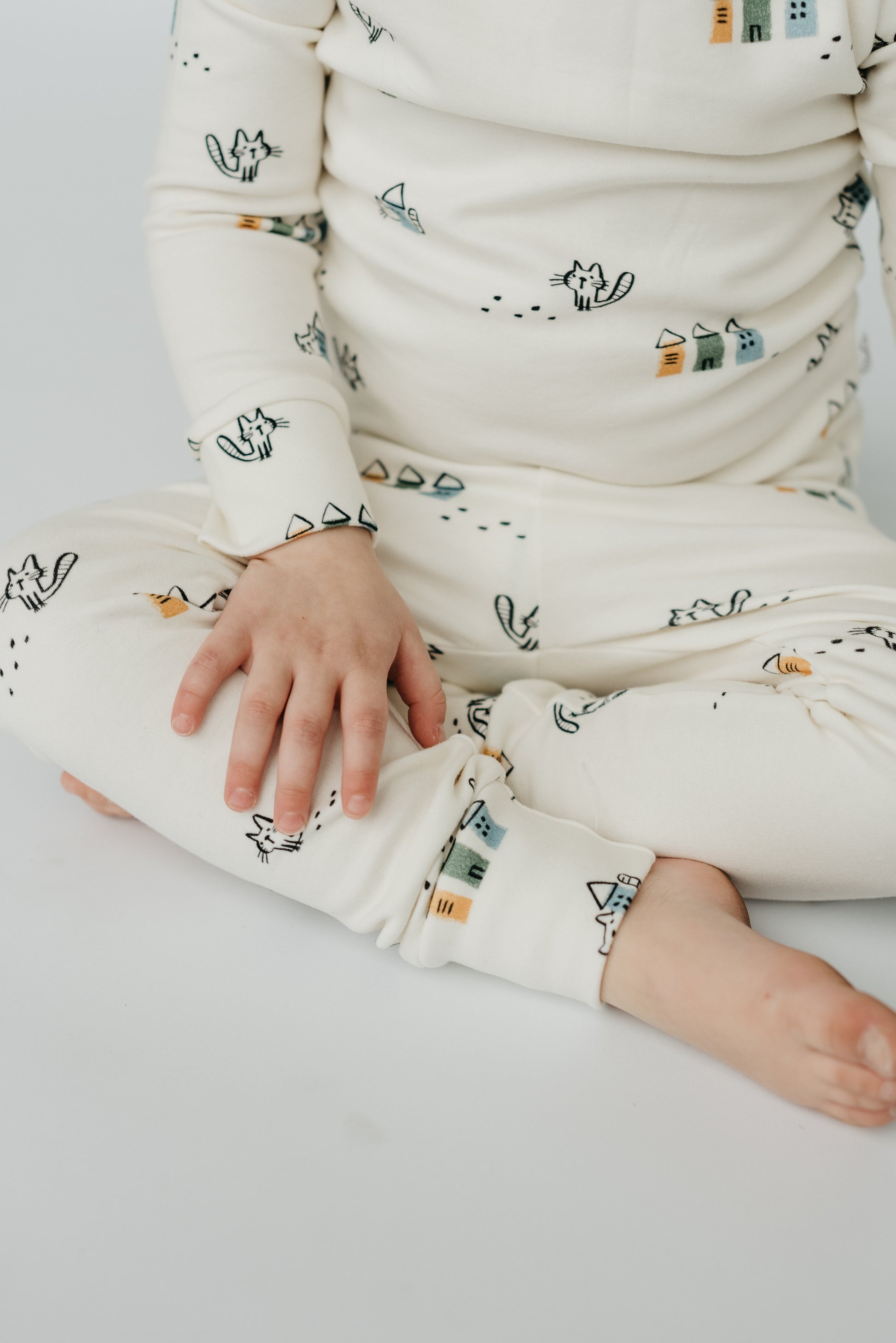 Baby wearing LURE by Lina Meow Construction sleeper — playful cotton blend pajamas with trucks and cats print for cozy all-day comfort