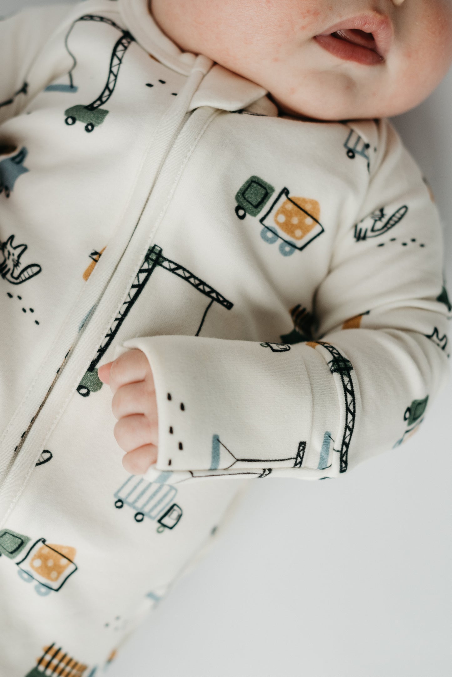 Close-up of Meow Construction print with cats, trucks, and plaid on soft cotton sleeper by LURE by Lina — two-way zipper and protective flap