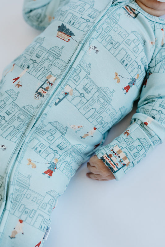 Baby wearing holiday baby sleeper for winter
Neutral aqua baby zip footie — LURE by Lina Merry Little Street print, two-way zip, double-stitched neckline.
