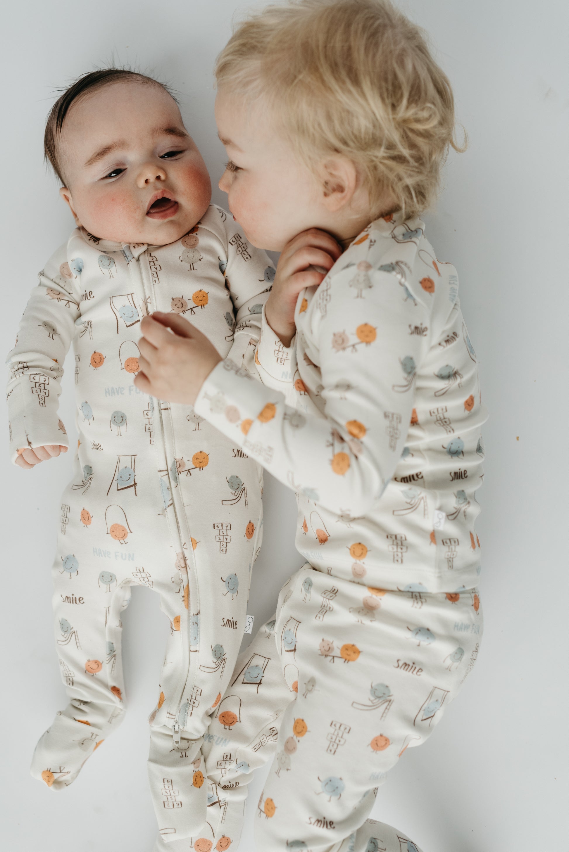 Sibling matching set in Play Time print — infant sleeper and toddler two-piece pajamas made from soft, breathable cotton blend by LURE by Lina